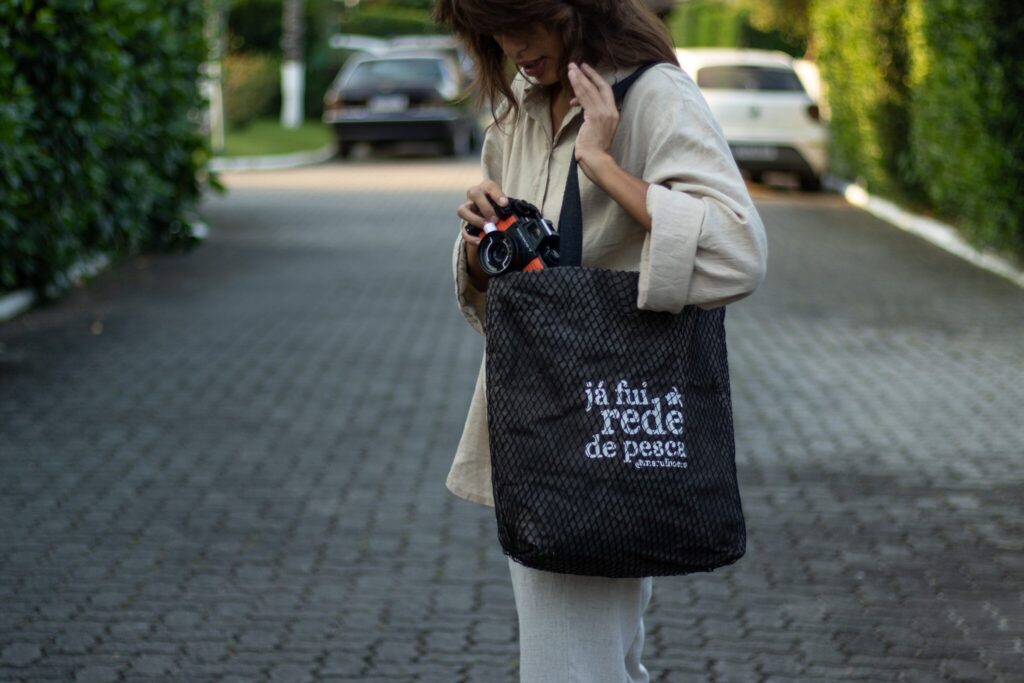 Pessoa carregando bolsa feita de rede de pesca com a frase já fui rede de pesca