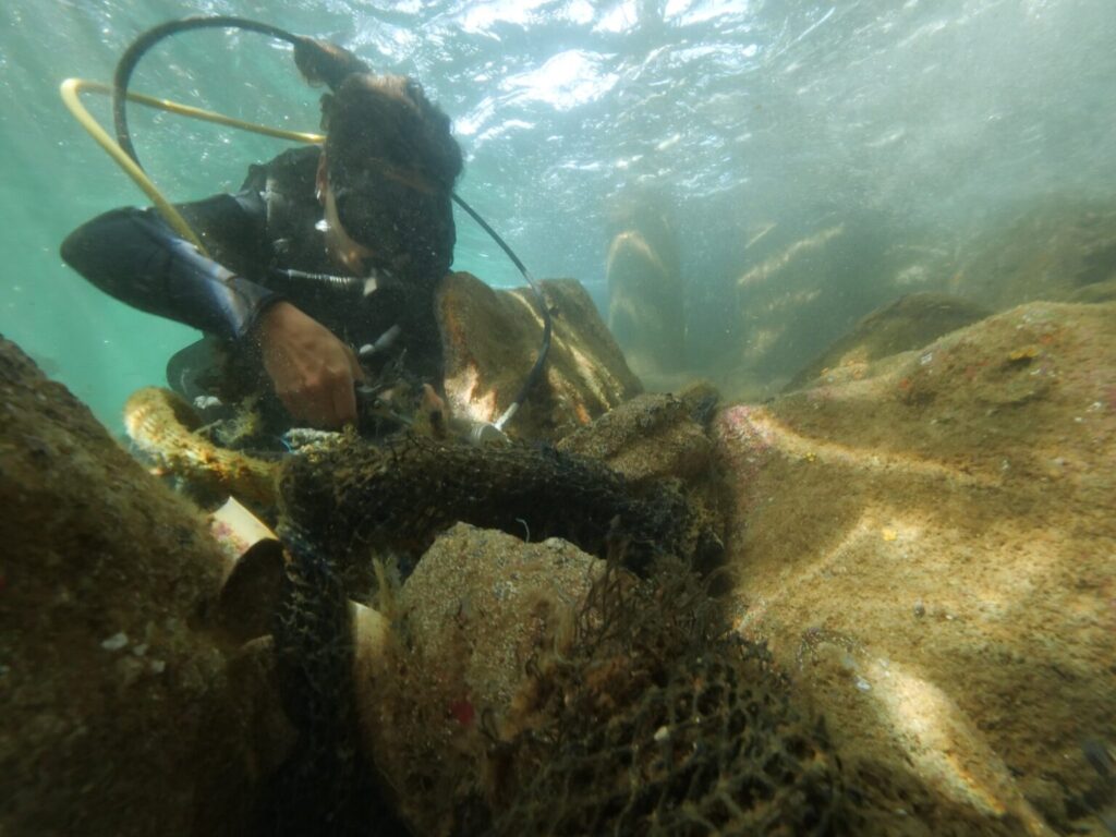 Mergulhador retirando rede fantasma do fundo do mar